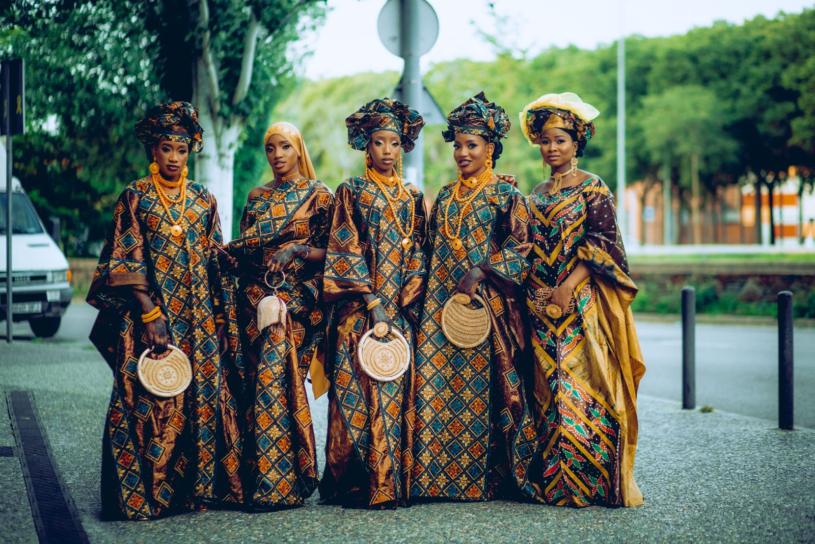A group of women in matching blue and gold outfits with fans at an outdoor ceremony