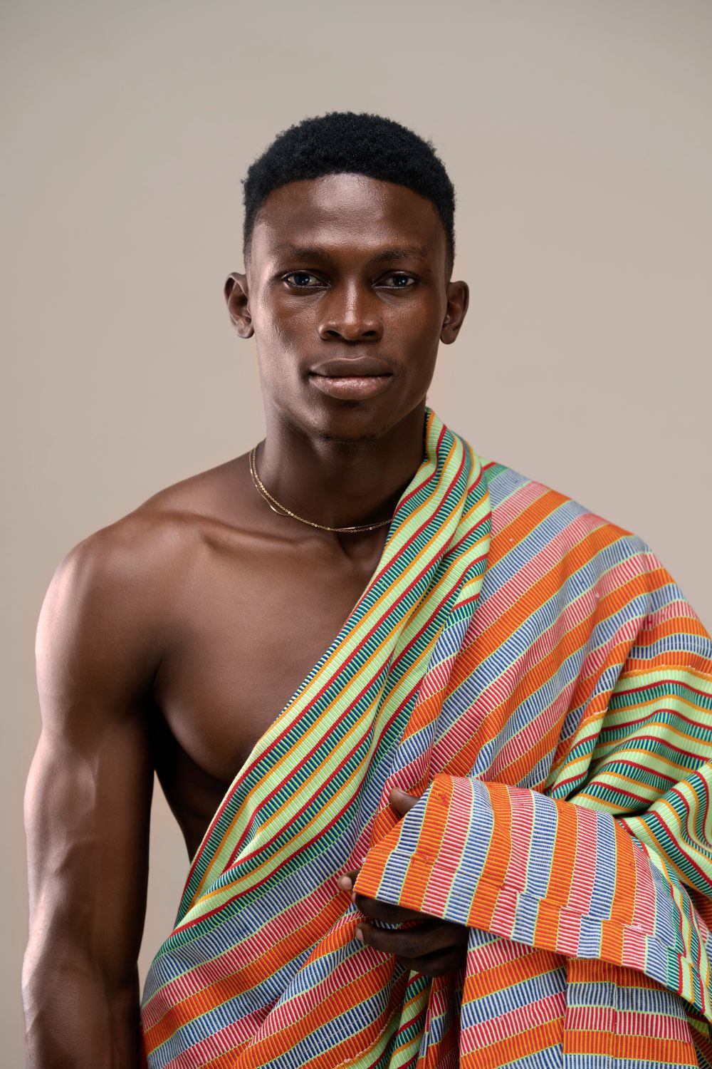 Young man wearing a length of kente cloth draped over one shoulder