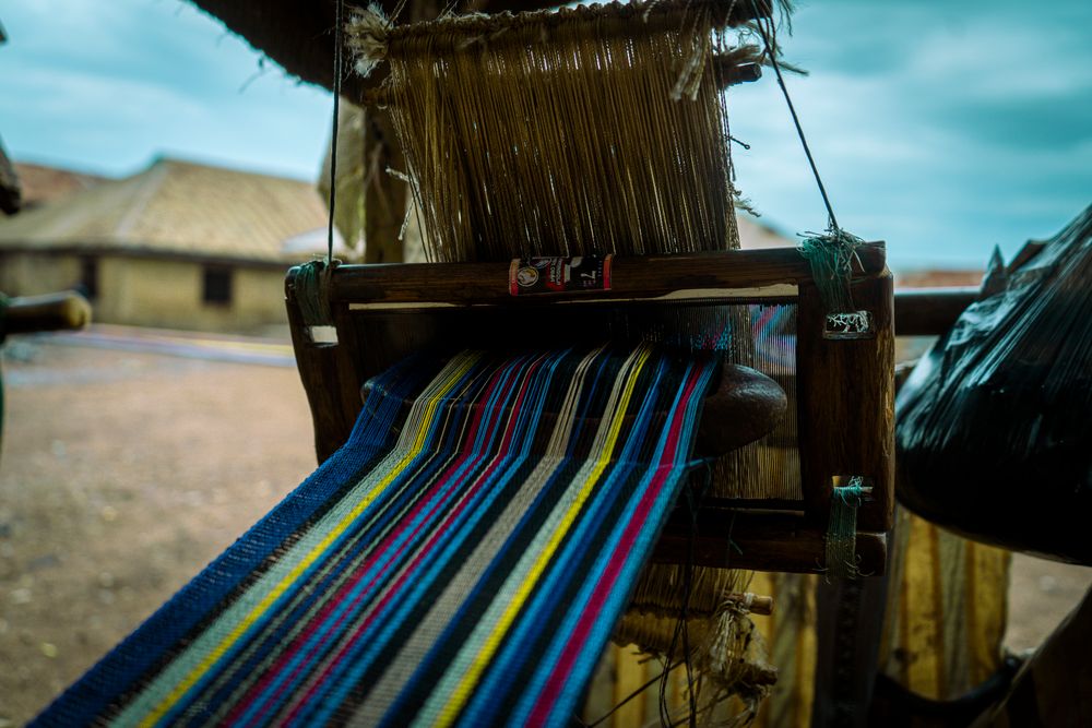 A narrow-strip weaving loom strung with coloured warp threads