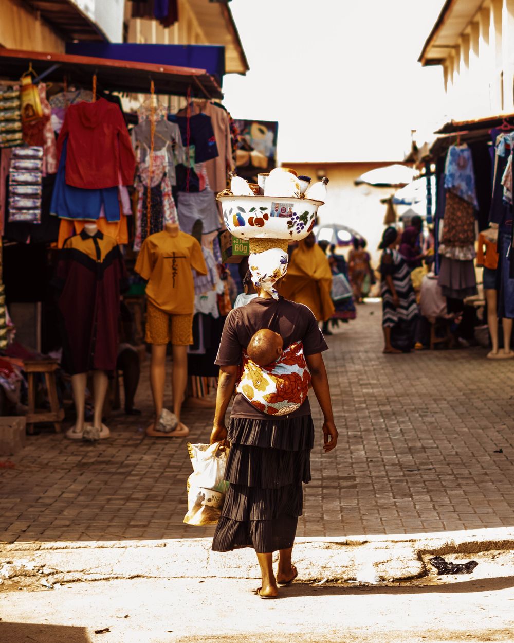 A busy outdoor market street lined with stalls and shoppers