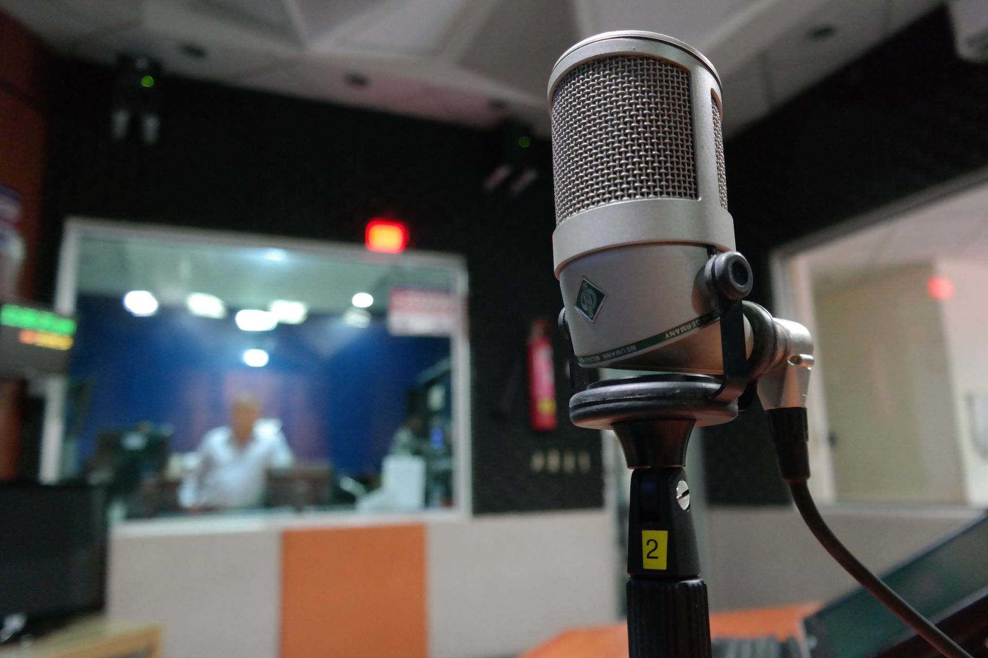 A broadcast studio desk with a microphone and mixing equipment